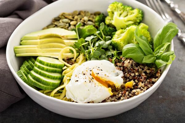 Table with fresh vegetables, herbs, and a prepared salad bowl
